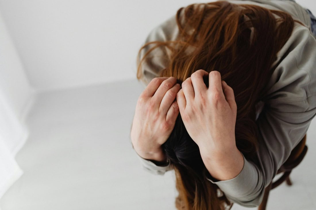 Crying woman with head in hands, psychological complaints and stress symptoms.